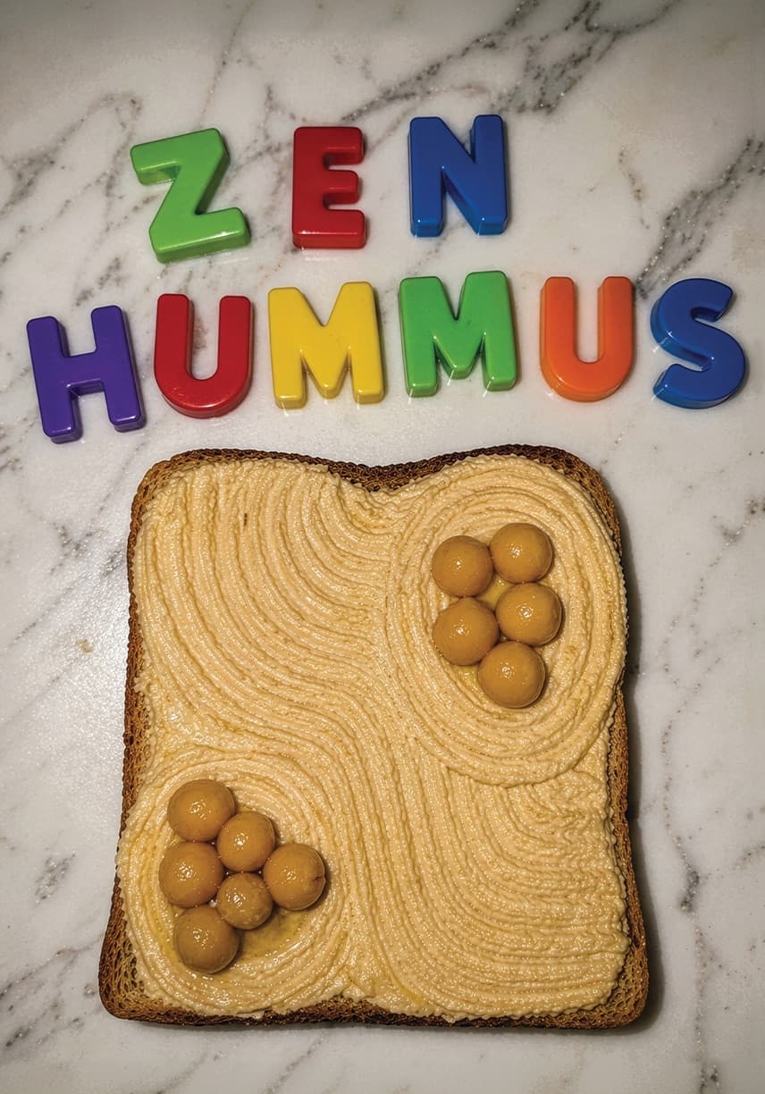 Fridge magnet letters spelling Zen Hummus above toast spread with raked hummus and chickpeas